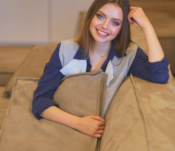 Woman sitting on her white sofa in white pullover.