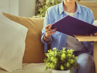 Genç bir kadın taşınıyor ve karton kutu paketliyor..