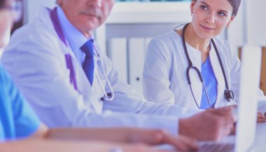 Parlak bir hastane odasında meslektaşlarıyla çalışan gülümseyen bir doktor.