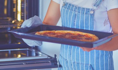 Mutlu genç bayan evde pizza pişiriyor..