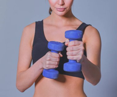 Atletik kadın dambıllarla kaslarını şişiriyor.