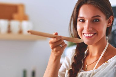 Mutfakta ahşap kaşıkla yemek pişiren kadın.