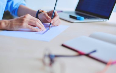 Ofis masasında dizüstü bilgisayarla oturan genç bir kadın. Genç bir kadın. Dizüstü bilgisayar.