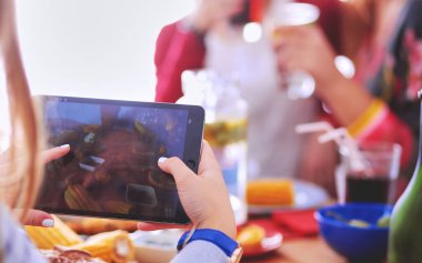 Ahşap masada otururken birlikte yemek yiyen bir grup insanın üst düzey görüntüsü. Masada yemek var. İnsanlar fast food yiyor.