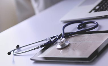 Tıbbi ekipman: Beyaz arka planda mavi steteskop ve tablet. Tıbbi ekipman.