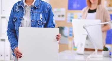 Masanın yanında duran iki genç kadın enstrüman, plan ve dizüstü bilgisayarla