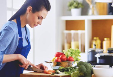 Mutfakta sebze doğrayan genç bir kadın..