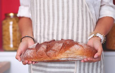 Genç bir kadın mutfağında ekmeği holding ayakta. Genç bir kadın.