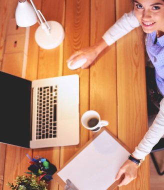 Masasında oturan ve elinde bir fincan kahveyle rahatlamış genç bir kadının portresi. İş kadını. İşyeri.