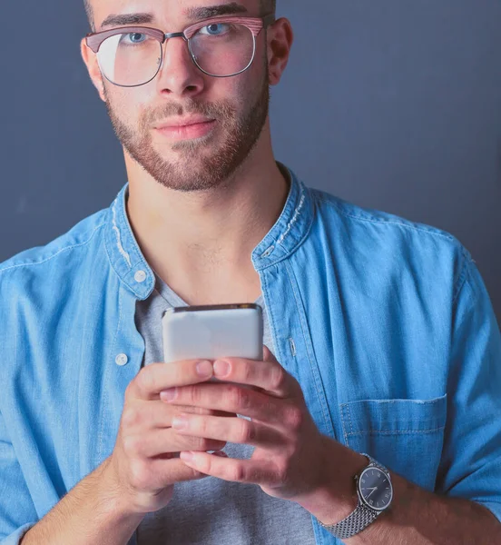 テキスト メッセージングながら若い男持株電話を笑顔 — ストック写真