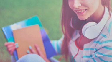 Yeşil çimlerde oturan genç bir kadın. Portreit genç bayan.