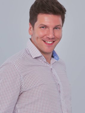 Zeki bir genç adam gri arka plan üzerinde ayakta portresi