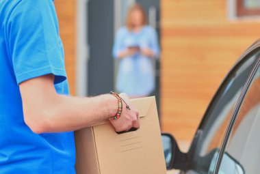 Mavi üniformalı gülümseyen kurye servis konseptine paket kutusu teslim eden teslimatçı. Mavi üniformalı gülümseyen teslimatçı..