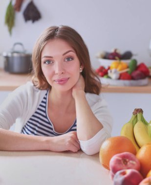 Mutfakta masanın yanında duran genç bir kadın..