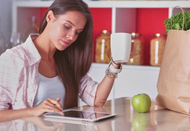 Mutfakta ipad 'ini kullanan genç bir kadın. Genç kadın..