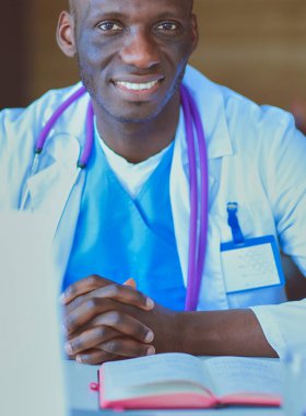 Masada dizüstü bilgisayarla çalışan genç bir Afrikalı doktor. Doktor bey. İşyeri.