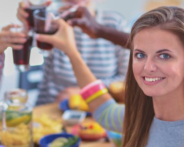 Ahşap masada otururken birlikte yemek yiyen bir grup insanın üst düzey görüntüsü. Masada yemek var. İnsanlar fast food yiyor. Bir kızın portresi..