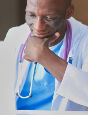 Masada dizüstü bilgisayarla çalışan genç bir Afrikalı doktor. Doktor bey. İşyeri.