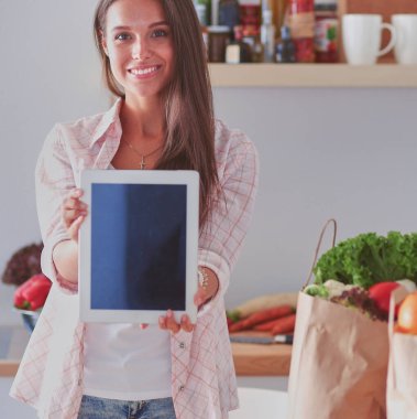 Mutfakta ipad 'ini kullanan genç bir kadın. Genç kadın..