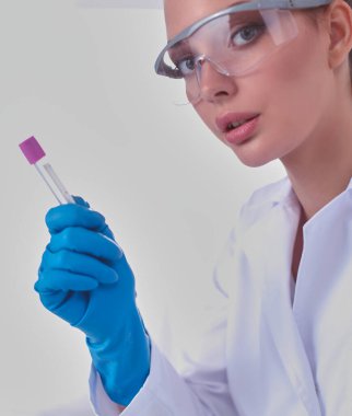 Kadın araştırmacı, beyaz şişeler ve şişelerle çevrili.