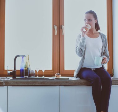 Mutfakta dijital tablet kullanan güzel genç bir kadın.