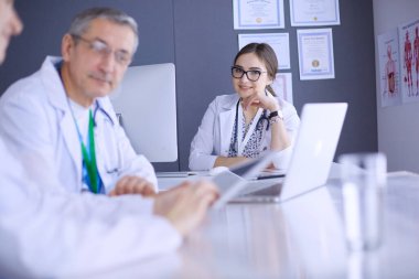 Ciddi bir tıbbi ekip parlak bir ofiste dizüstü bilgisayar kullanıyor..