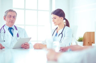 Ciddi bir tıbbi ekip parlak bir ofiste dizüstü bilgisayar kullanıyor.