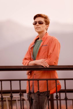 Kasabada turuncu gömlekli yakışıklı bir genç var.