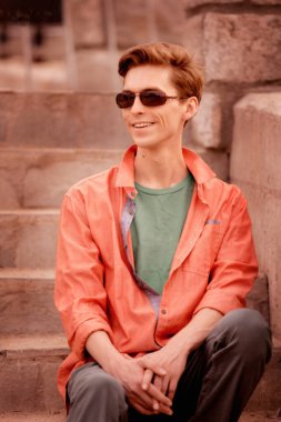 Bir yakışıklı genç adam merdivenlerde oturuyor.