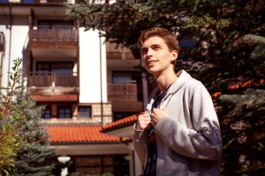 Yakışıklı adam şehirde dikilip poz veriyor.