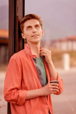 Elinde kahve fincanı olan yakışıklı bir genç adam.