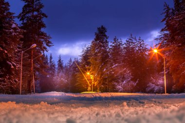 Bulgaristan 'ın Bansko kenti ve aydınlık kayak yolu yamacı ve alacakaranlıkta Pirin dağı zirveleri manzaralı Bulgar kış kayak merkezi manzarası