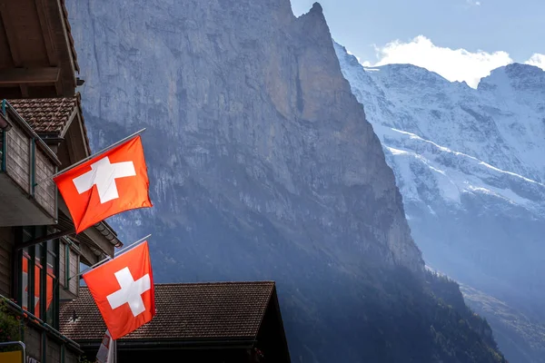 Alpendorpshuizen met vlaggen, Zwitserse Alpen, Zwitserland — Stockfoto
