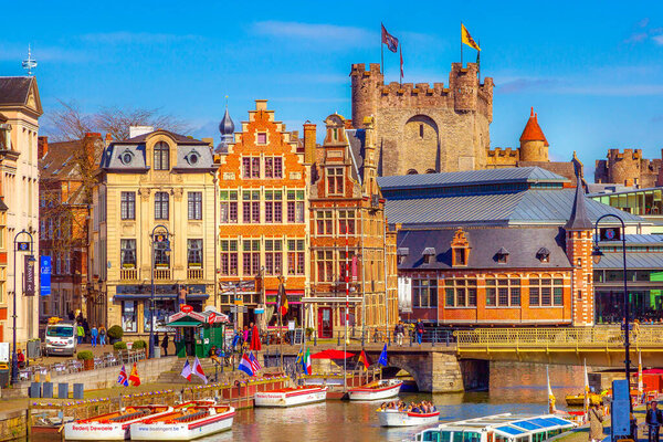 Ghent, Belgium - April 12, 2016: Old colorful traditional houses along the canal, boats, Gravensteen castle in Gent