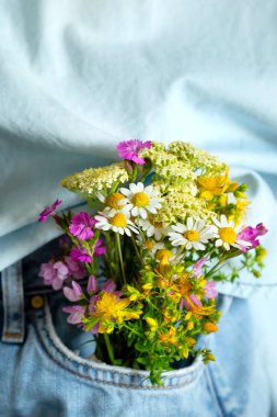 Kot pantolonun ön cebinde güzel narin çiçekler, yakın plan, yaz aşkı romantik konsepti.