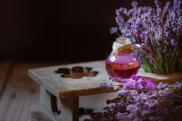 Herbal oil and lavender flowers still-life on wooden background