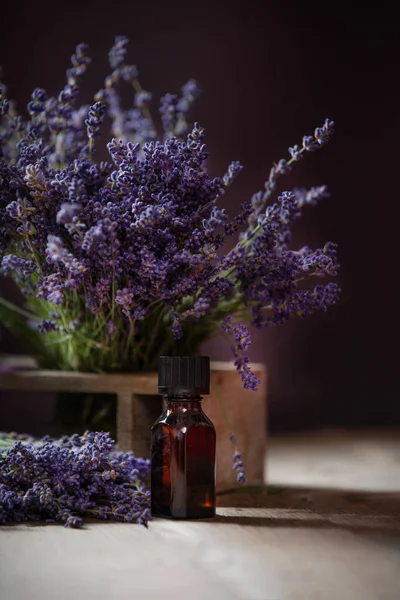 Herbal oil and lavender flowers still-life on wooden background