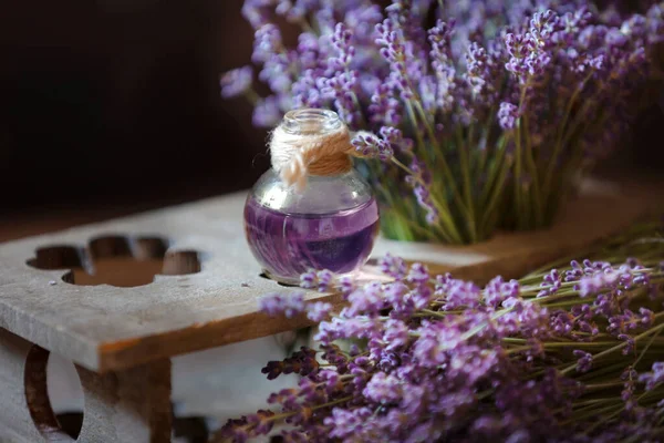 Herbal oil and lavender flowers still-life on wooden background