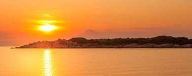 Mount Athos in Greece at sunset, bright sunrise in the early summer morning, orange sun, banner background