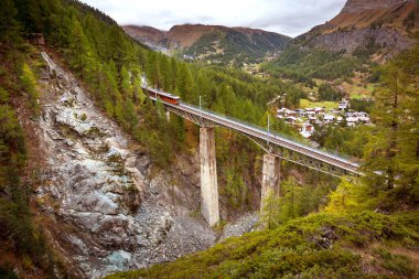 Zermatt, Switzerland. Gornergrat red tourist train on the bridge in Swiss Alps panorama