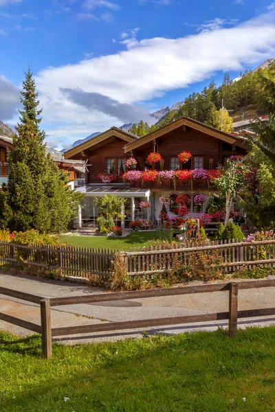 Yazın penceresinde sardunya çiçekleri olan geleneksel tahta dağ evi, Zermatt alp köyü, İsviçre, İsviçre Alpleri