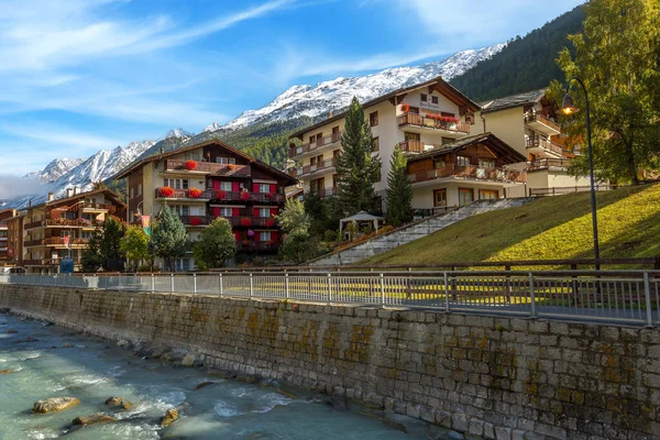Zermatt, Switzerland - October 7, 2019: Town street view in famous Swiss Alps ski resort, river, snow mountain peaks