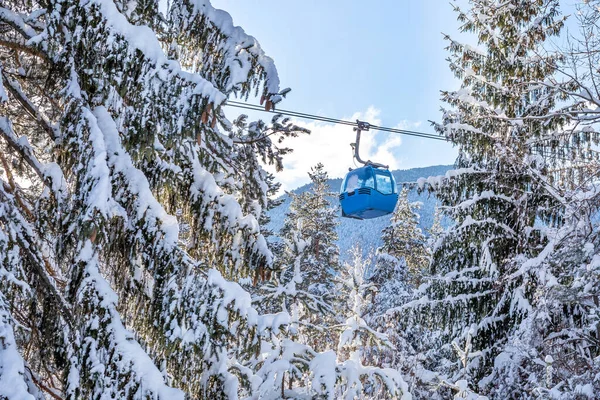 Winter resort with ski lift gondola cabins and snow mountains and pine trees after snowfall, Bansko, Bulgaria