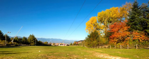 Bansko, Bulgaria autumn landscape banner with wooden fence, colorful trees and gondola lift station