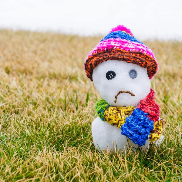 Unhappy snowman melting on green grass — Stock Photo, Image