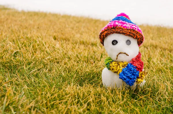 Unhappy snowman melting on green grass — Stock Photo, Image