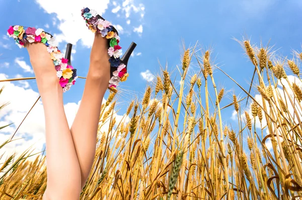 Vackra kvinnliga ben på blå himmel och vete fält — Stockfoto