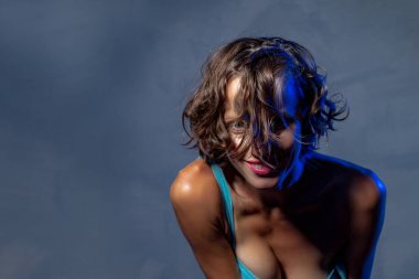 Gri arka planda poz veren şehvetli güzel kadın.