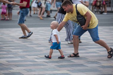 Ukrayna, Mariupol - 9 Ağustos 2021: Baba oğluyla birlikte şehrin merkezinde yürüyor