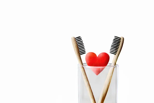 白い背景の上に2本の歯ブラシと赤いハートが隔離されています 愛とバレンタインデーのコンセプト 竹環境に優しい歯ブラシ — ストック写真